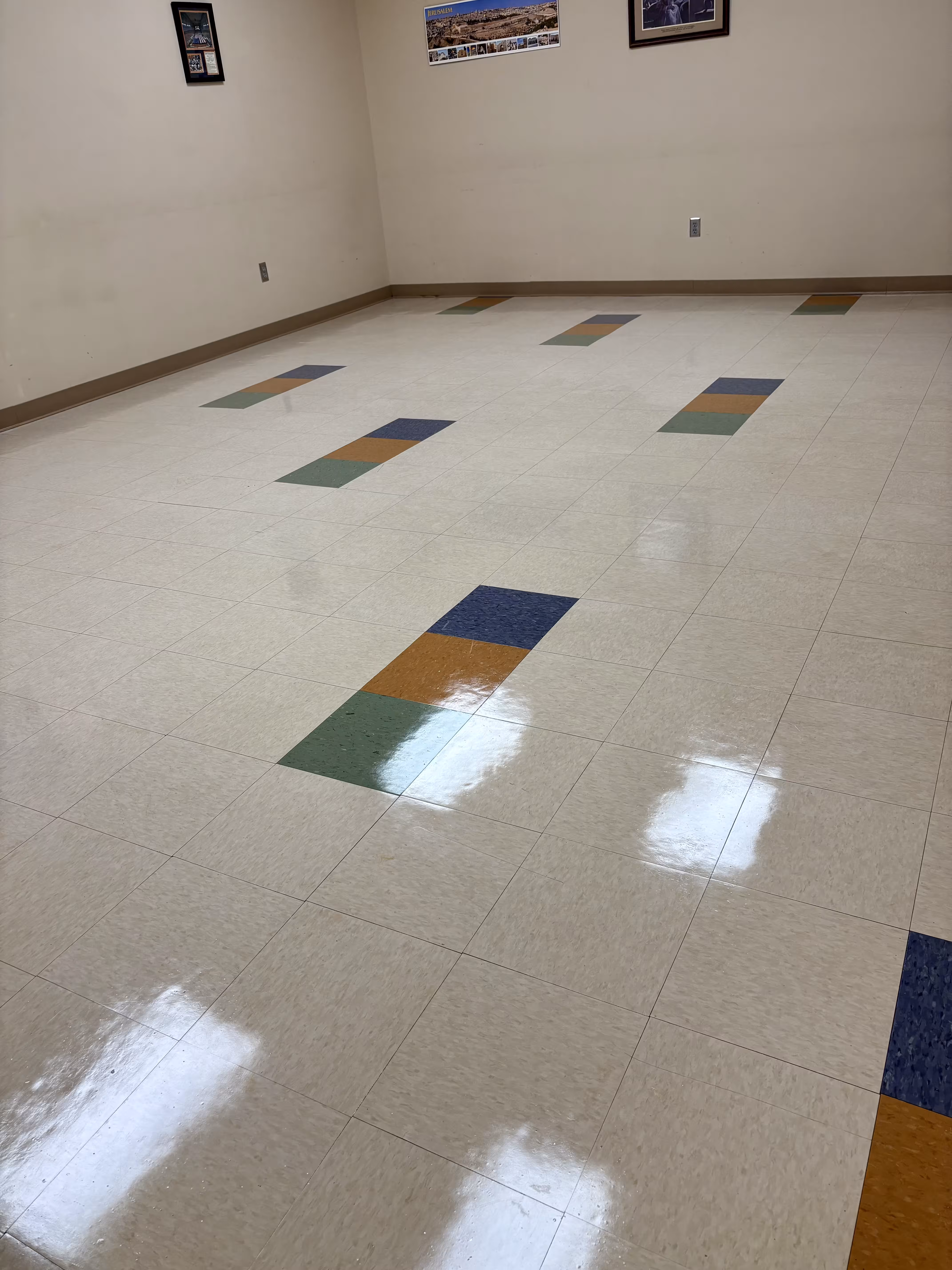 Freshly stripped and waxed VCT floor with a high-gloss finish and colored accent tiles
