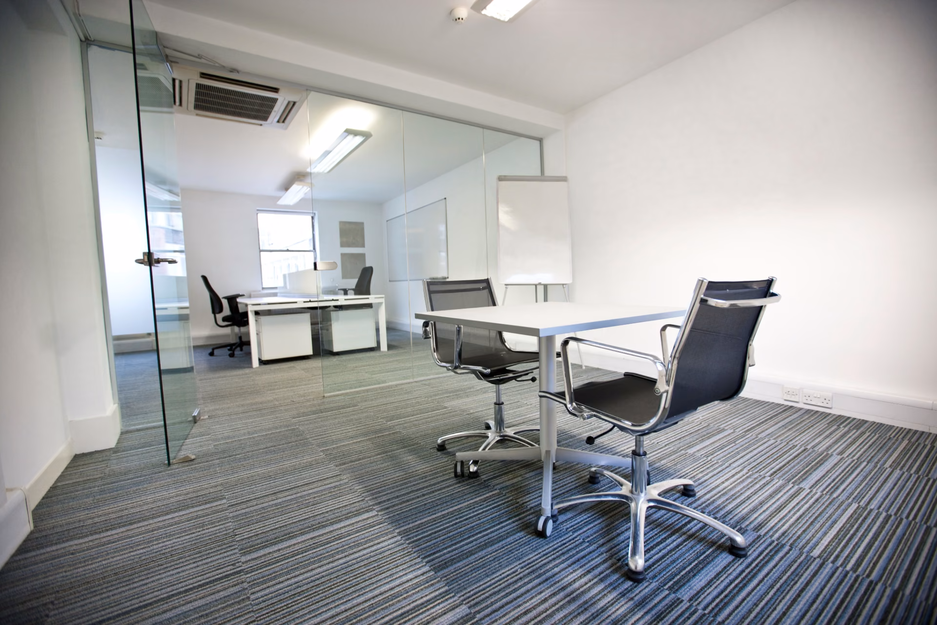 Spotless modern office meeting room with vacuumed carpet and clean glass partitions, reflecting a complete office cleaning checklist