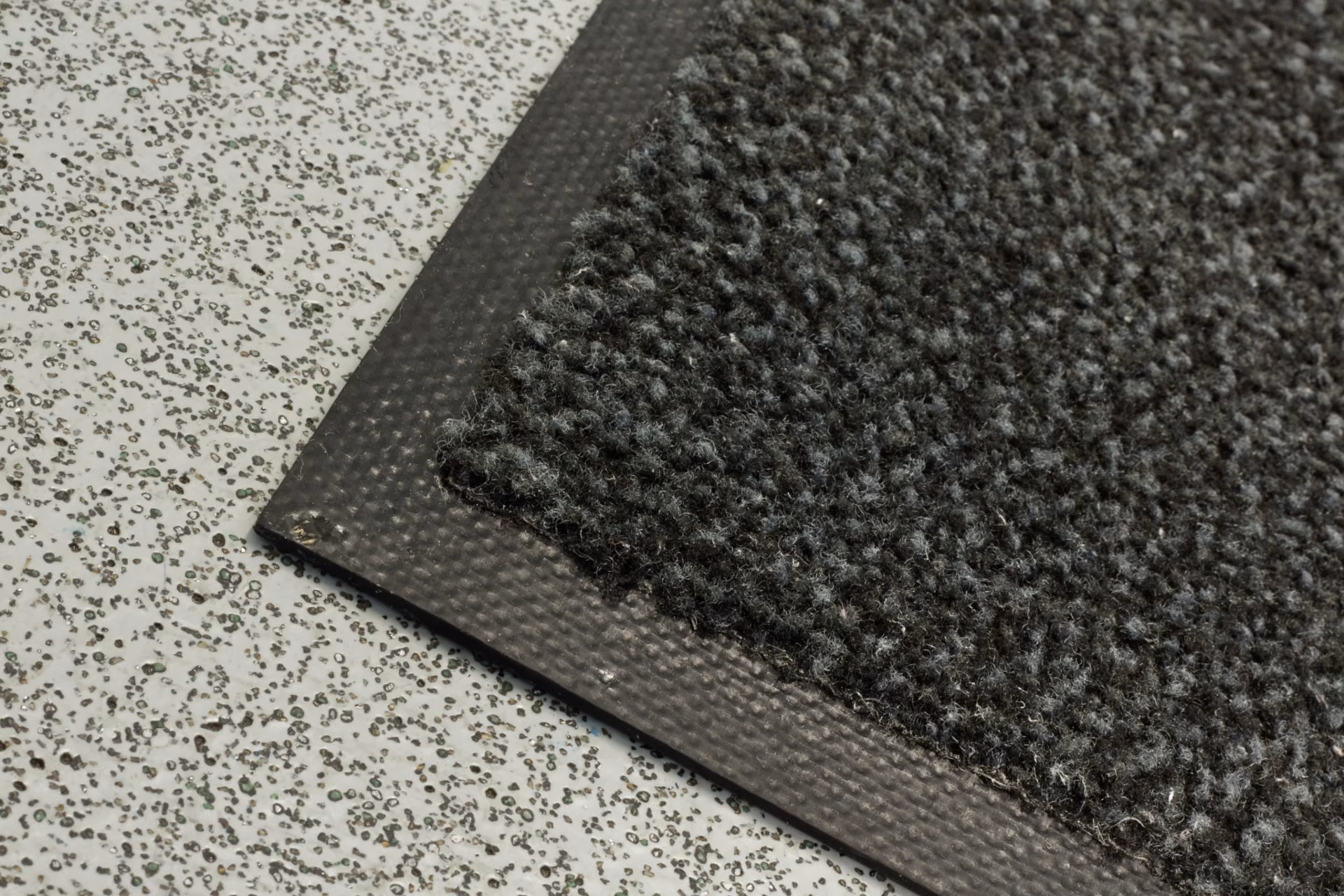 Close-up of a commercial walk-off entrance mat protecting a facility floor from tracked-in dirt and grit