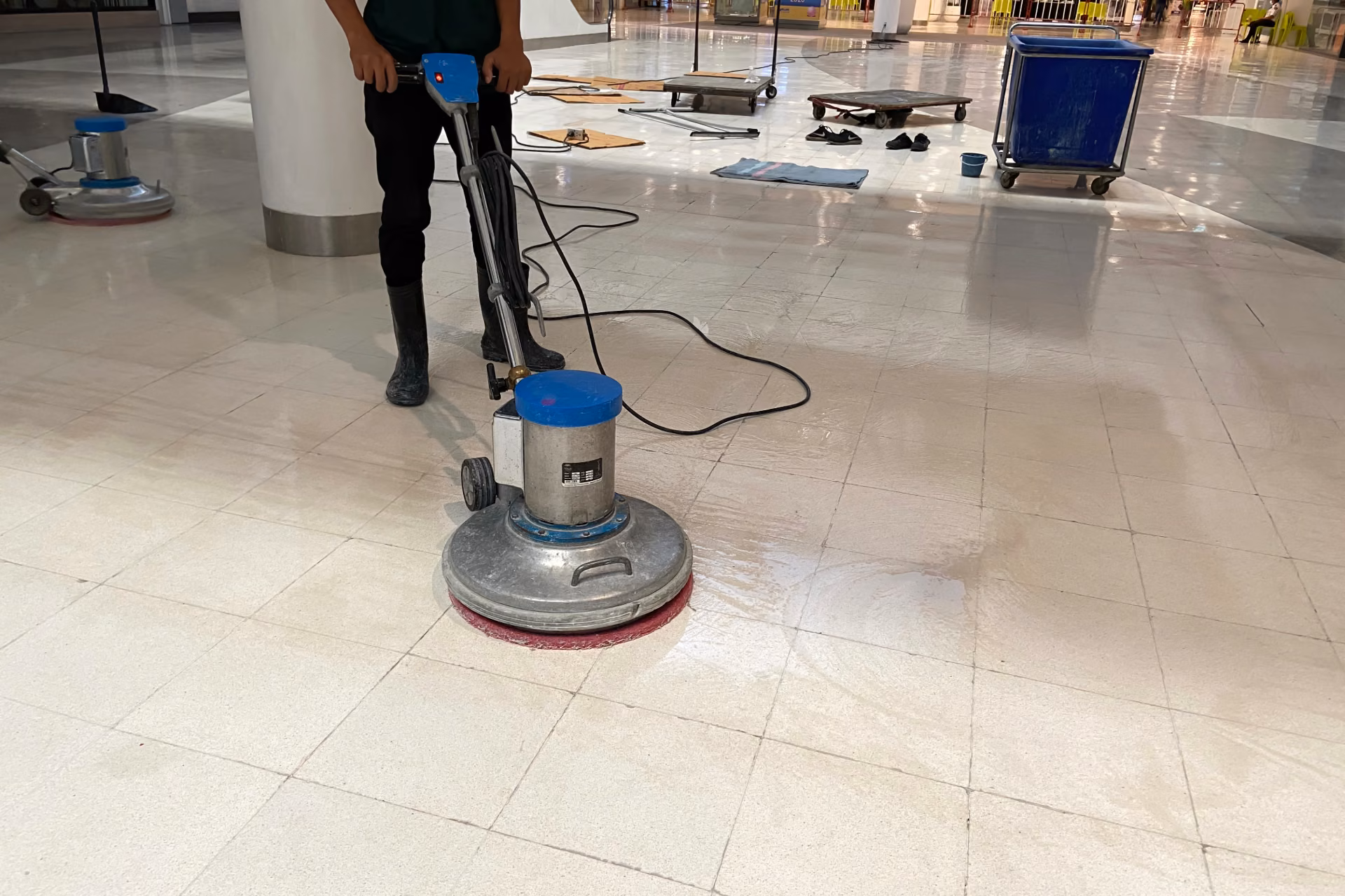 Commercial cleaning technician using a floor buffing machine to maintain and restore gloss on a VCT tile floor