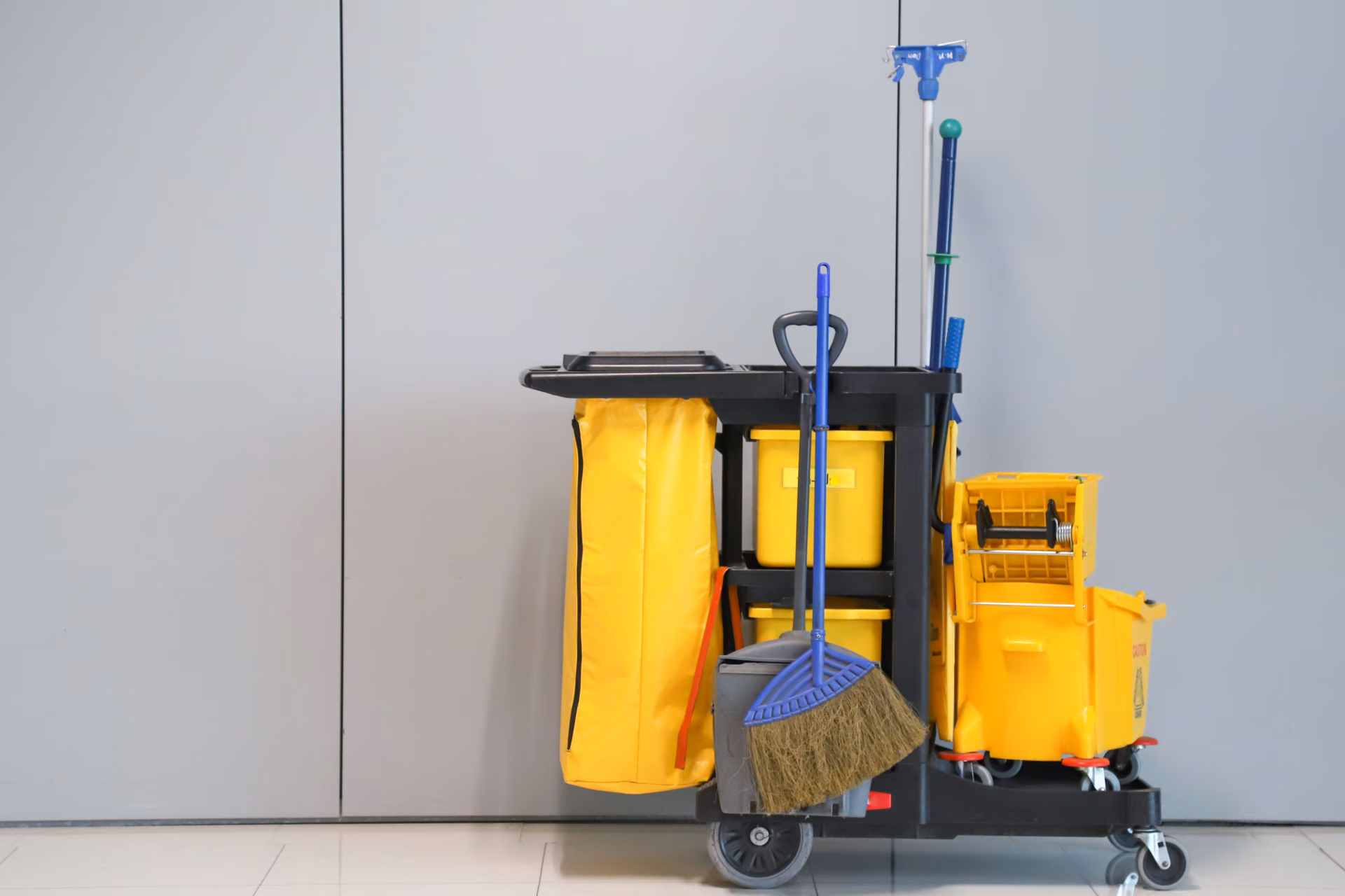 Fully stocked commercial janitorial cleaning cart with mop, broom and supplies, representing a professional janitorial service contract scope