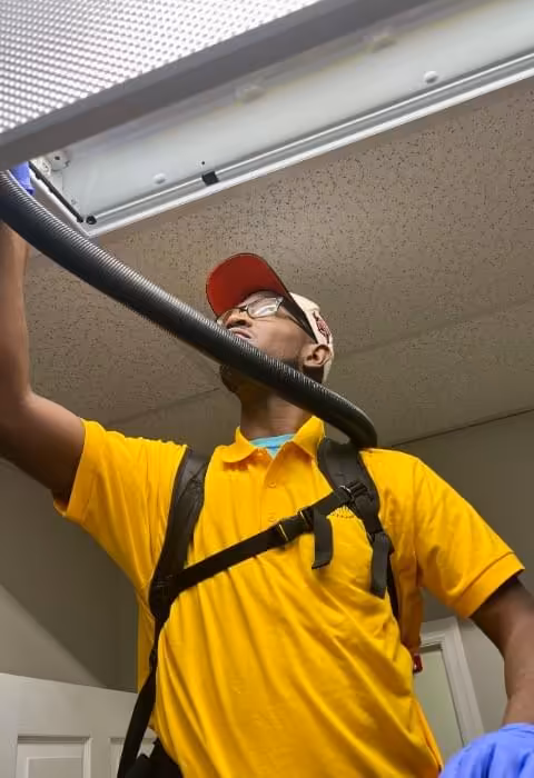 Sweepers technician vacuuming ceiling air vents during a regular office cleaning in Gadsden, AL